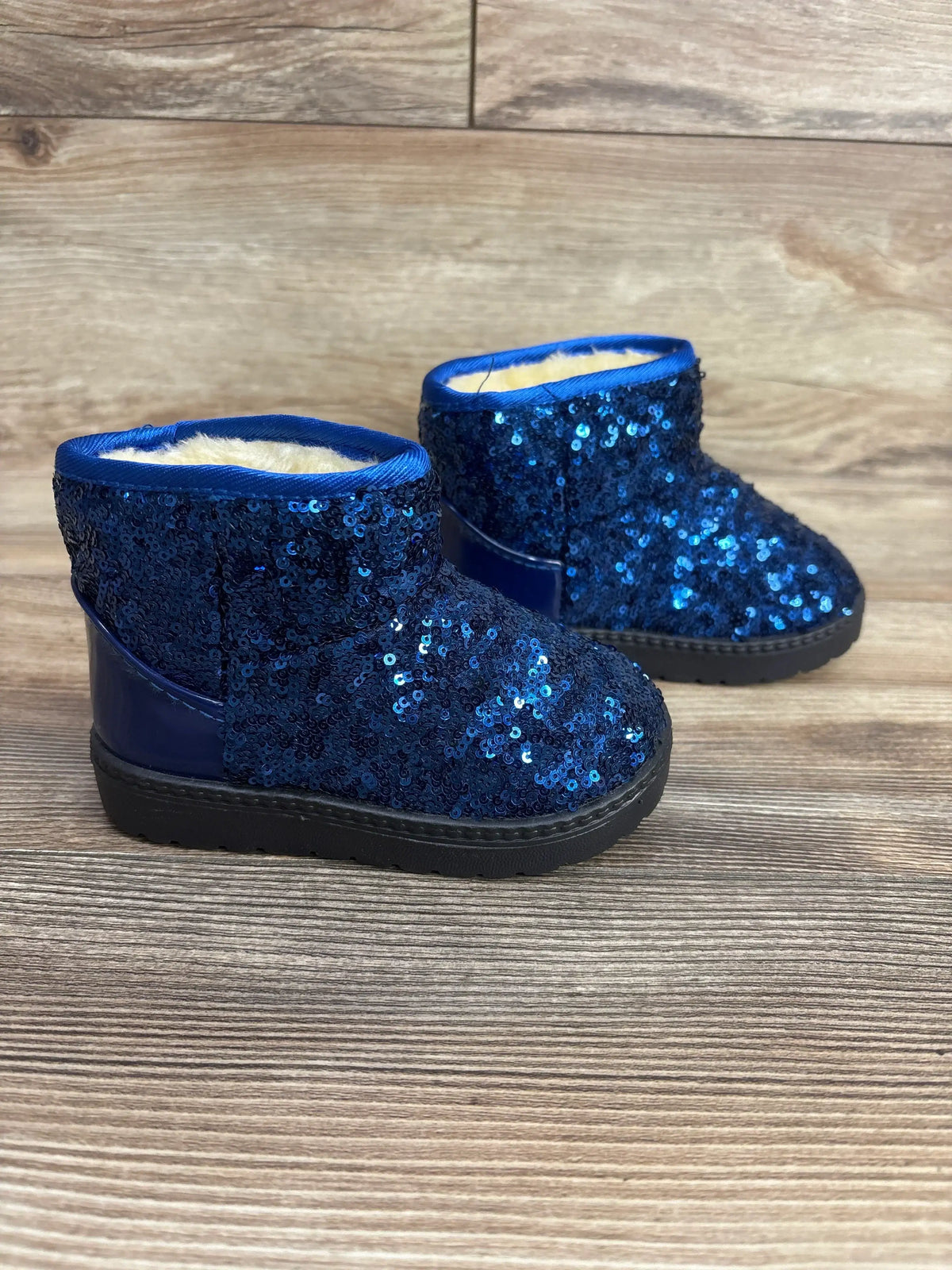 Blue sequin toddler boots with faux fur lining on wood background