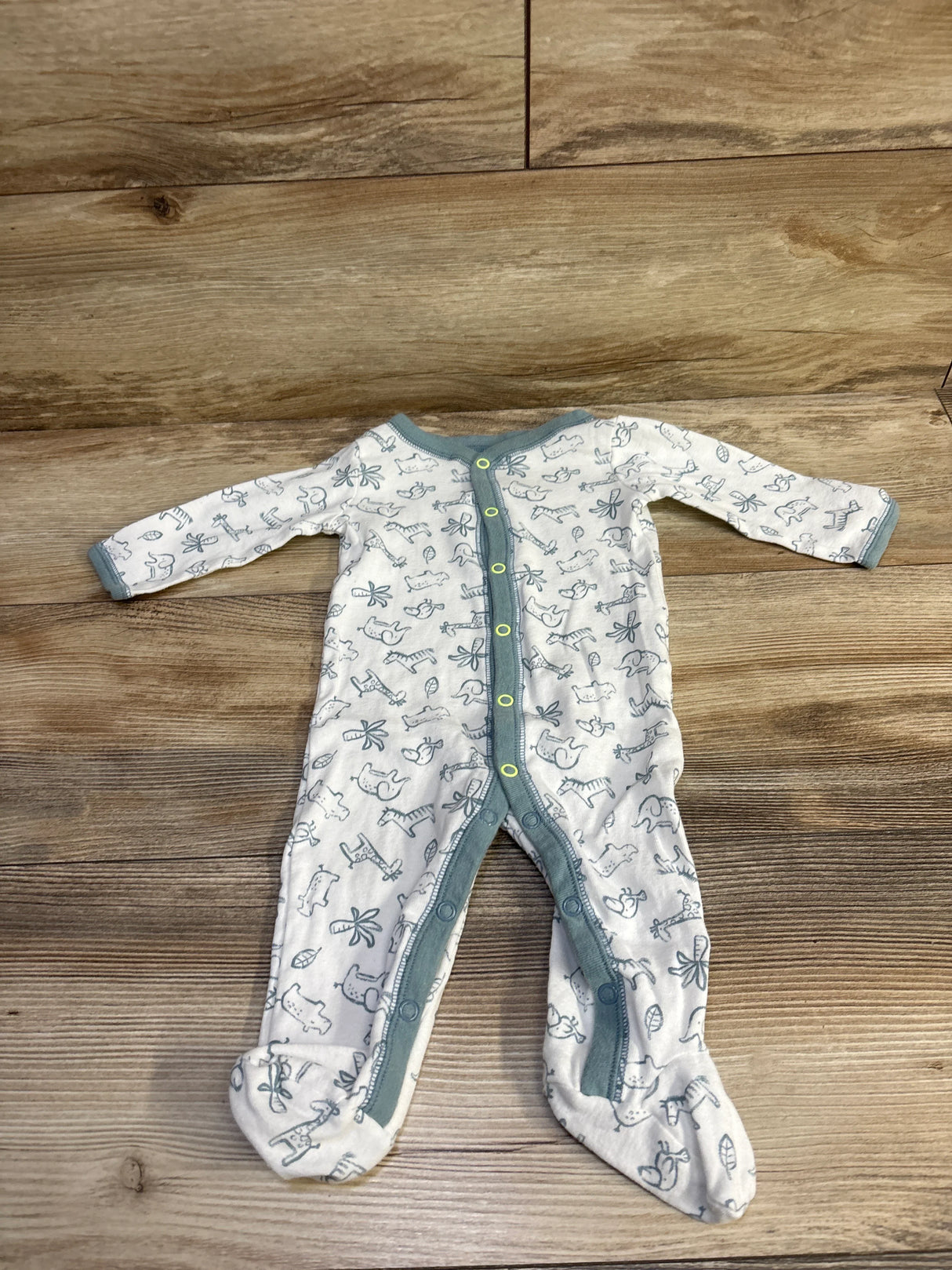 Flat-lay front view of white footed baby snap sleeper with teal trim and gray animal print on wood background