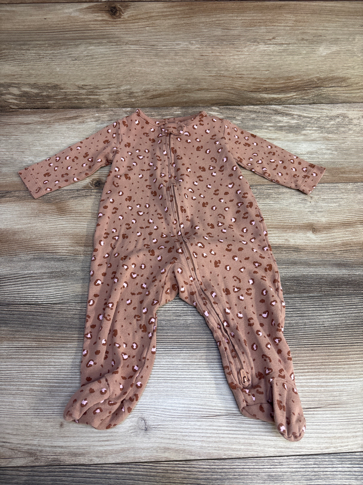 Leopard print baby footed sleeper with zipper on rustic wooden background