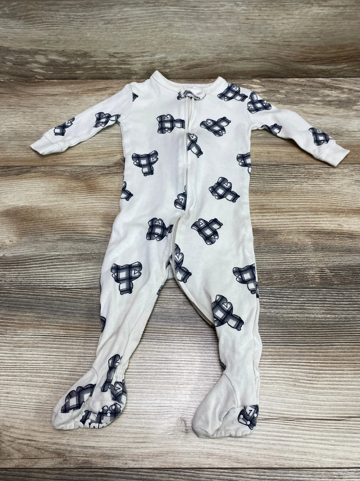 Flat lay of beige Baby Gap footed sleeper with navy bear-print pattern and full front zipper on light wood surface