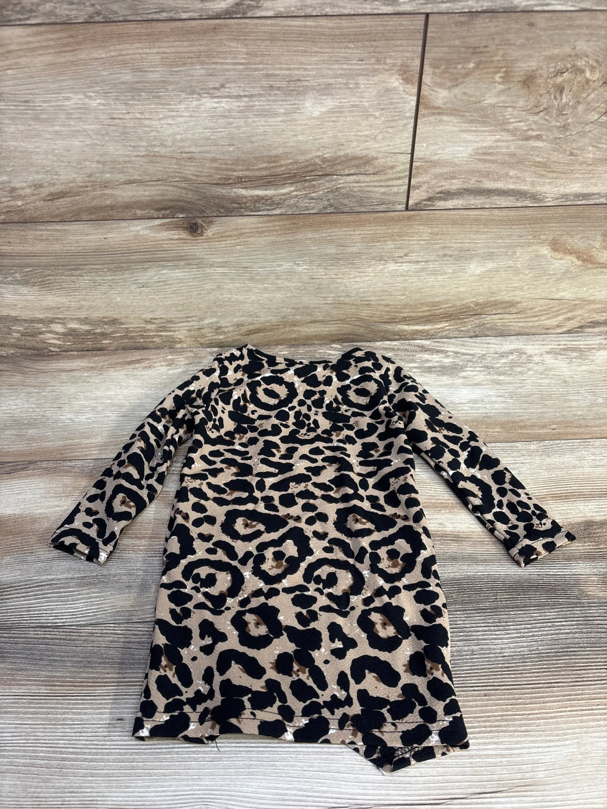 Flat lay of toddler leopard-print long-sleeve dress showing beige and black pattern on wood floor