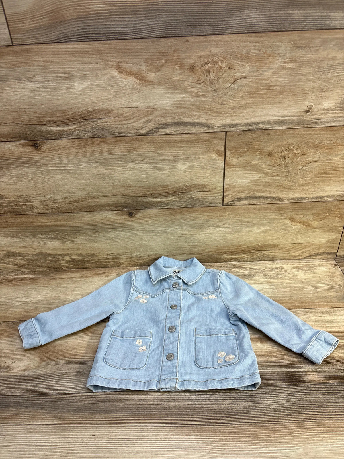 Light blue OshKosh embroidered denim jacket for toddlers, size 2T, on a wood background