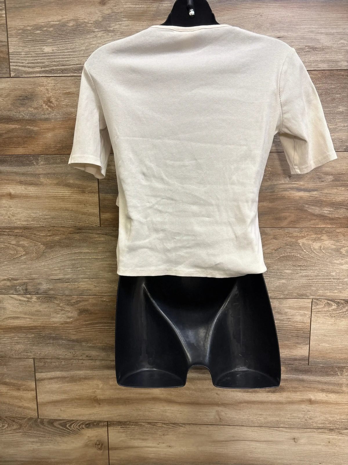 Back view of H and M Mama ribbed nursing shirt in ivory on black mannequin with wood background