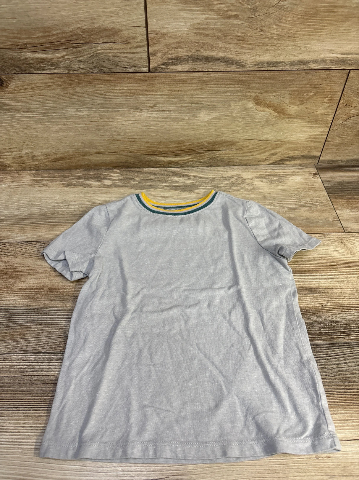 Flat lay of grey Old Navy toddler tee size 5T showing green and yellow striped neckline on wood background
