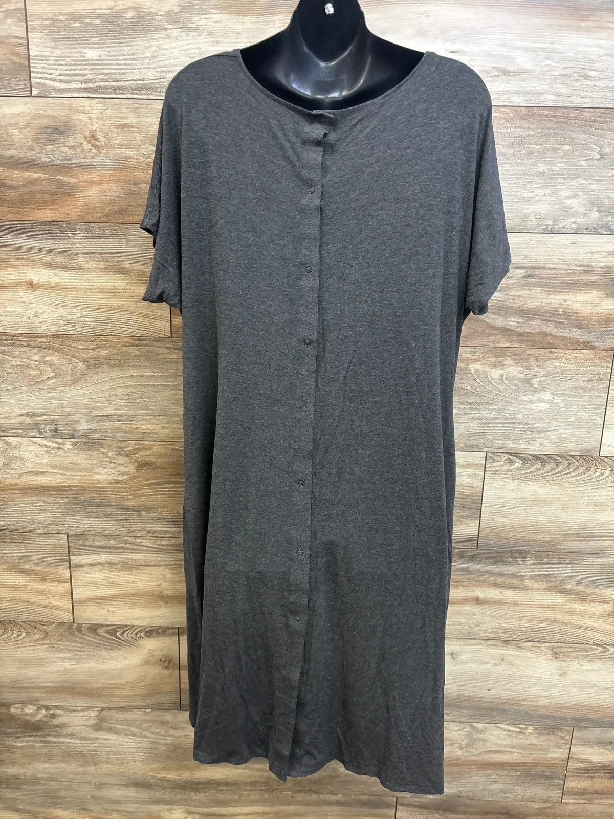Front view of grey Frida delivery and nursing gown on mannequin showing front snap closure, short sleeves, and soft knit fabric against wood panel background