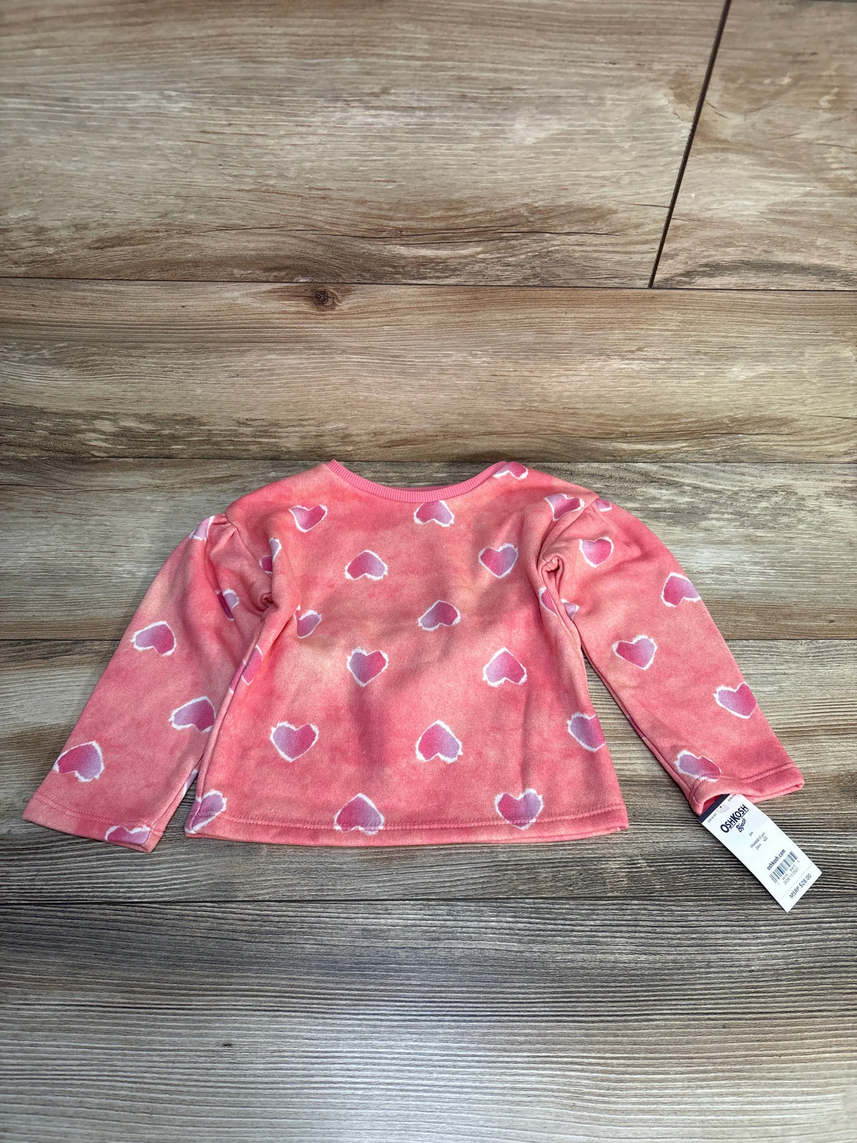 Pink toddler long sleeve shirt with white heart pattern on wood background