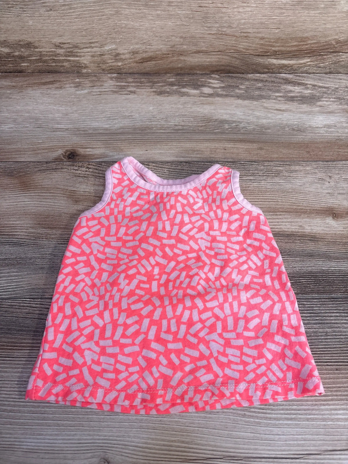 Flat lay of pink Okie Dokie tank top size 9 months showcasing white confetti-style sprinkle pattern on wood background