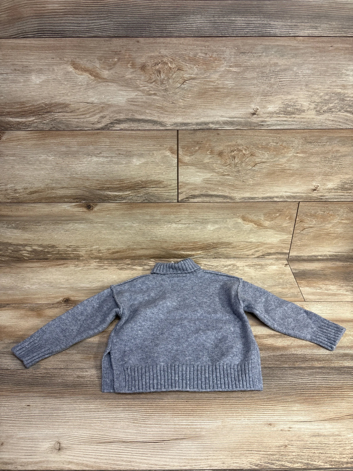 Gray children's knit sweater with long sleeves on wood background