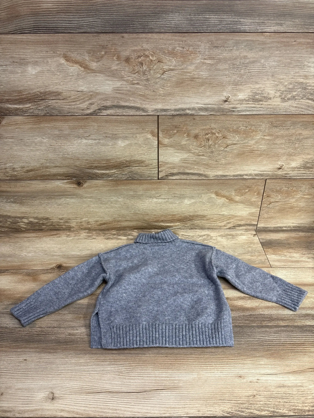 Gray children's knit sweater with long sleeves on wood background