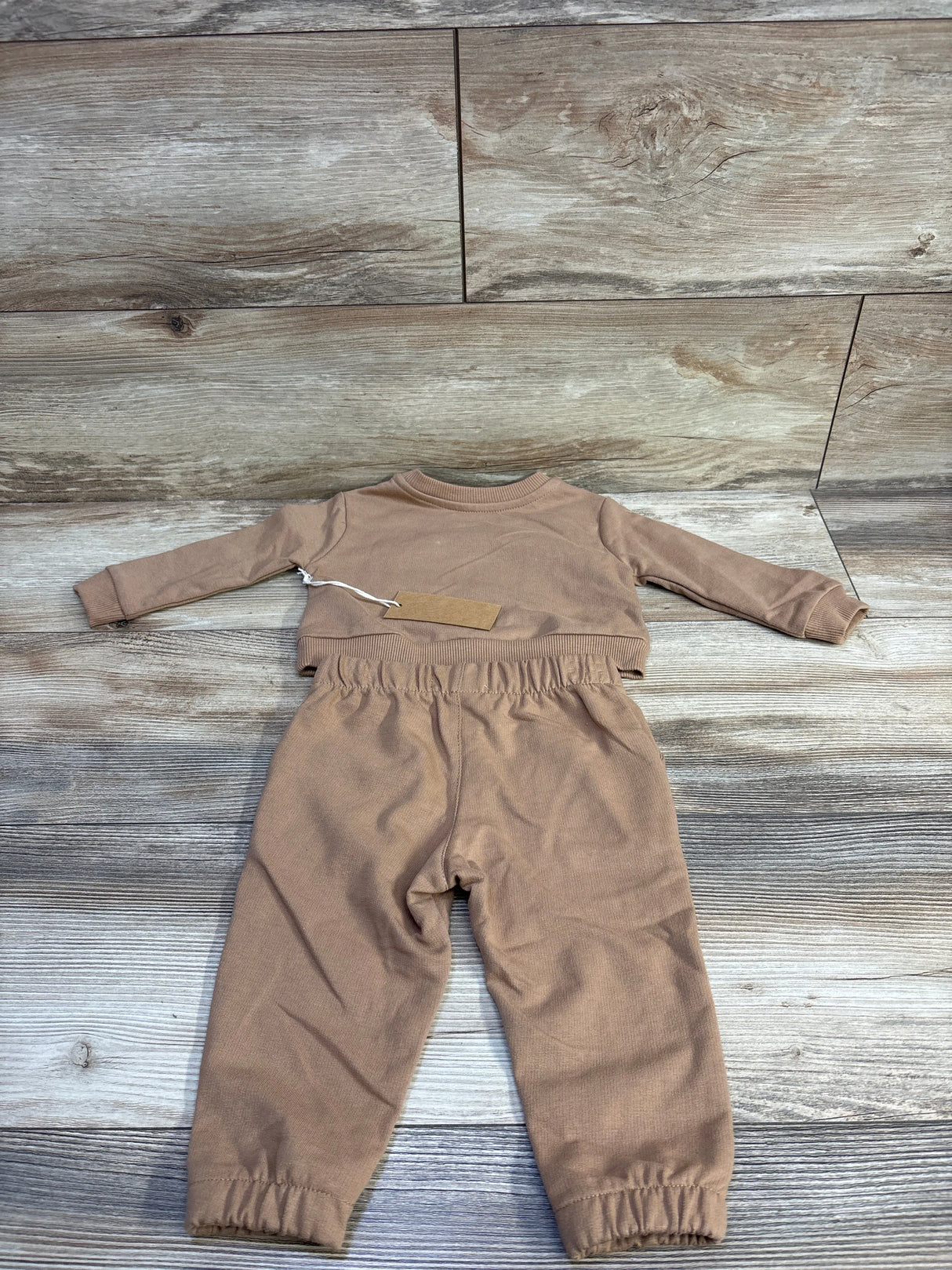 Flat lay of Stitch and Stone brown 2-piece sweatshirt and joggers (9M) showing elastic waistband and ankle cuffs on wood floor