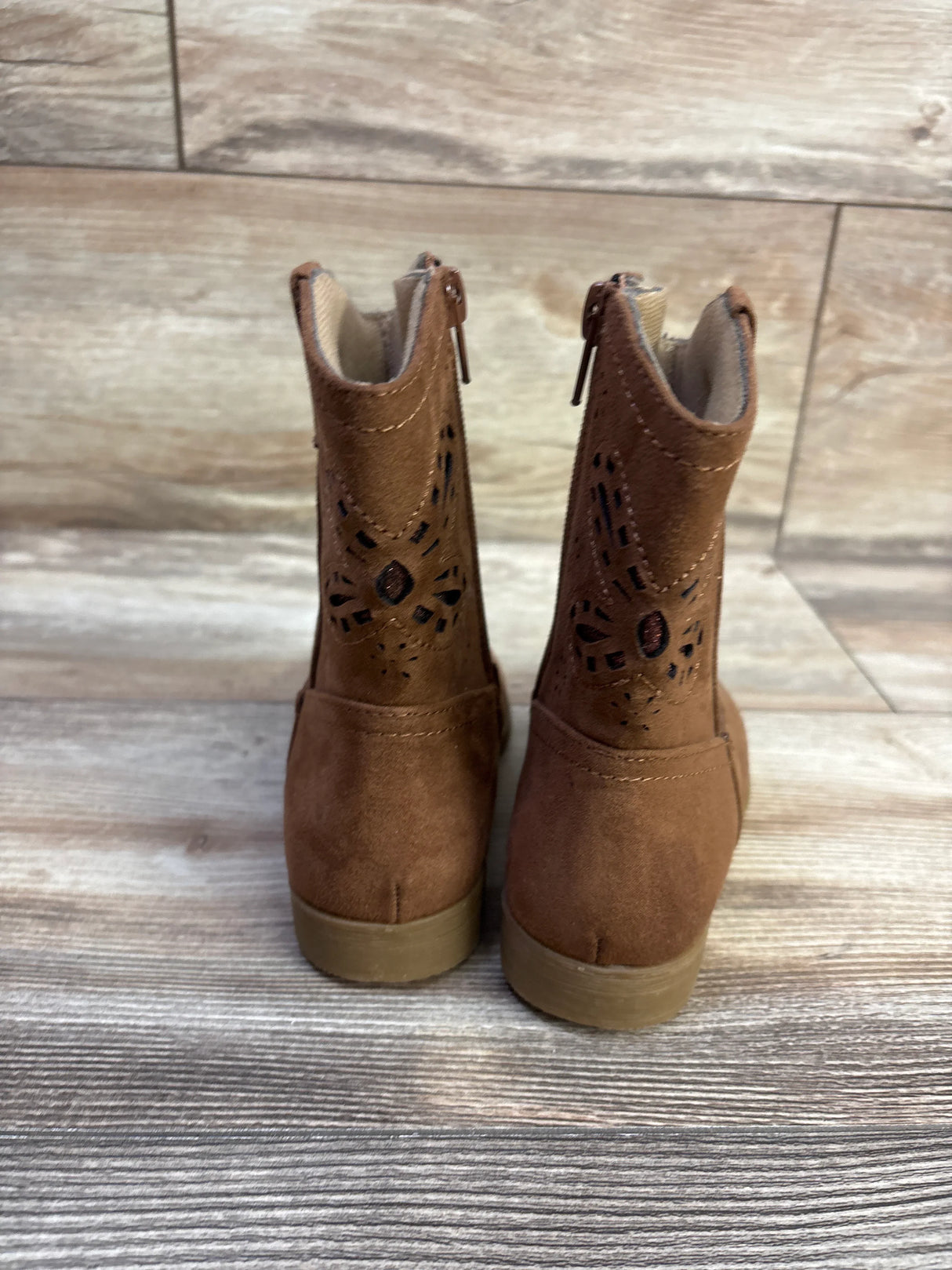 Rear view of Rachel Shoes Lil Jayla toddler western boots in brown showcasing laser cut floral shaft detail and back zippers on wood floor background