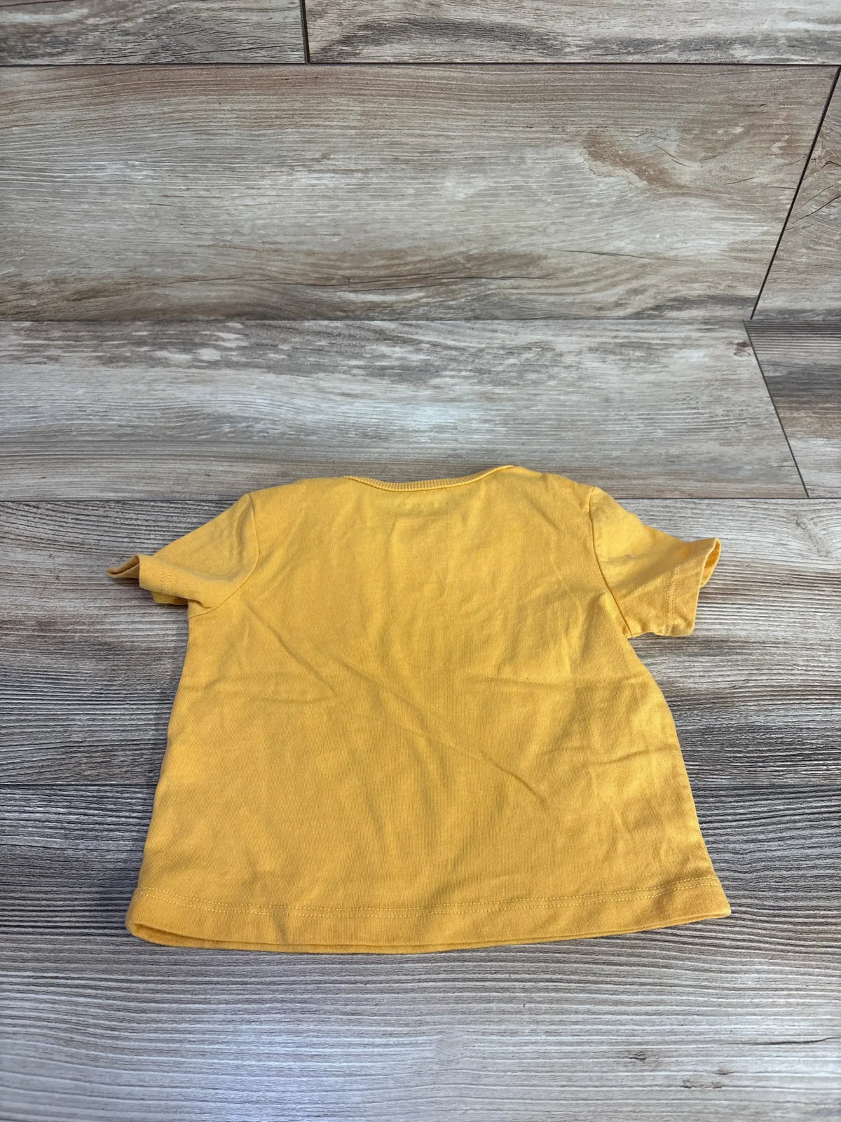Back view of yellow First Impressions baby pocket shirt in size 6 to 9 months showcasing short sleeves on a wood-look floor