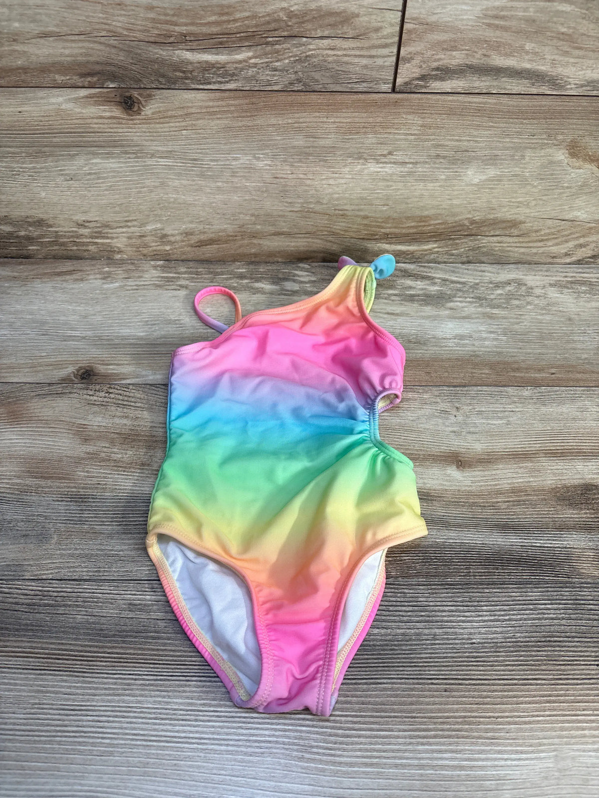 Cat & Jack toddler rainbow gradient one-piece cut-out swimsuit on a wooden background