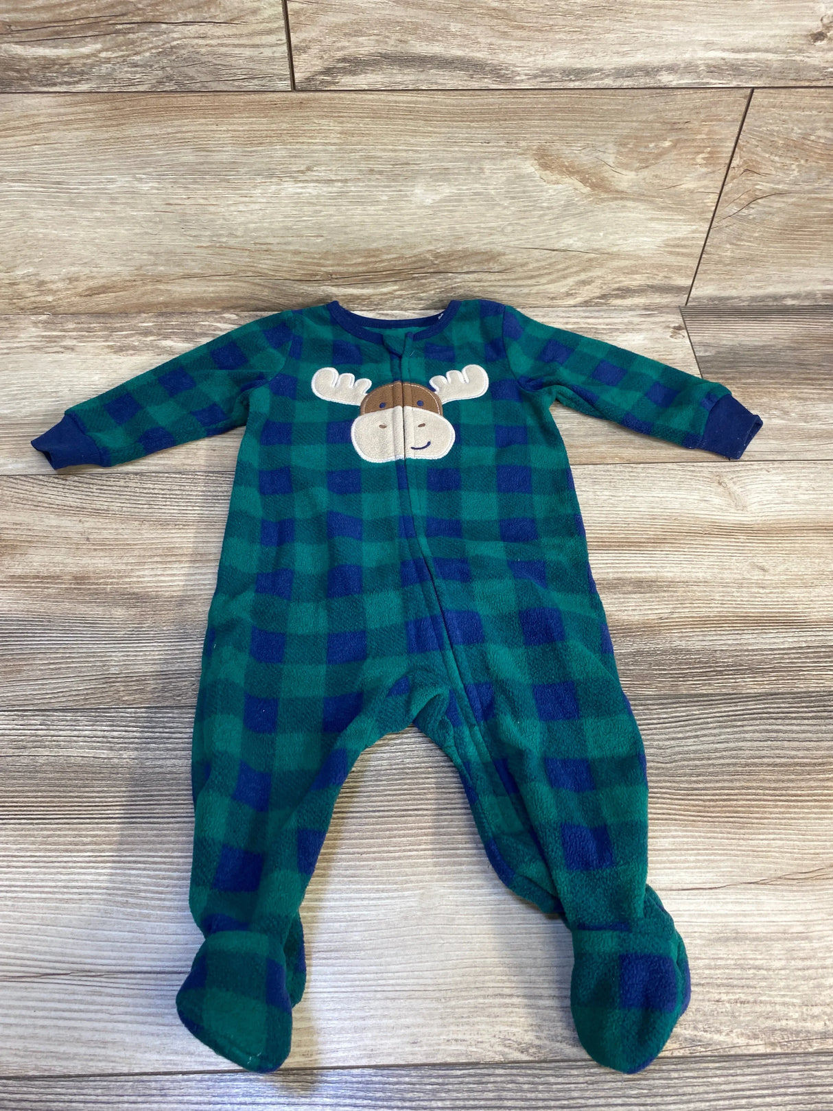 Green and blue plaid baby sleeper with moose design, footed pajamas on wood floor