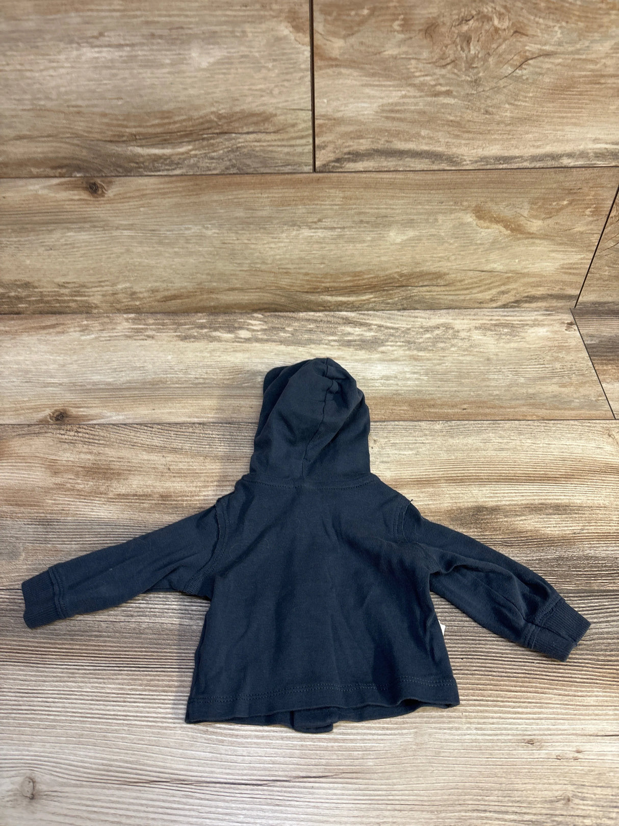 Back view of Carter’s newborn hooded button-front shirt showcasing hood and ribbed cuffs on wood background