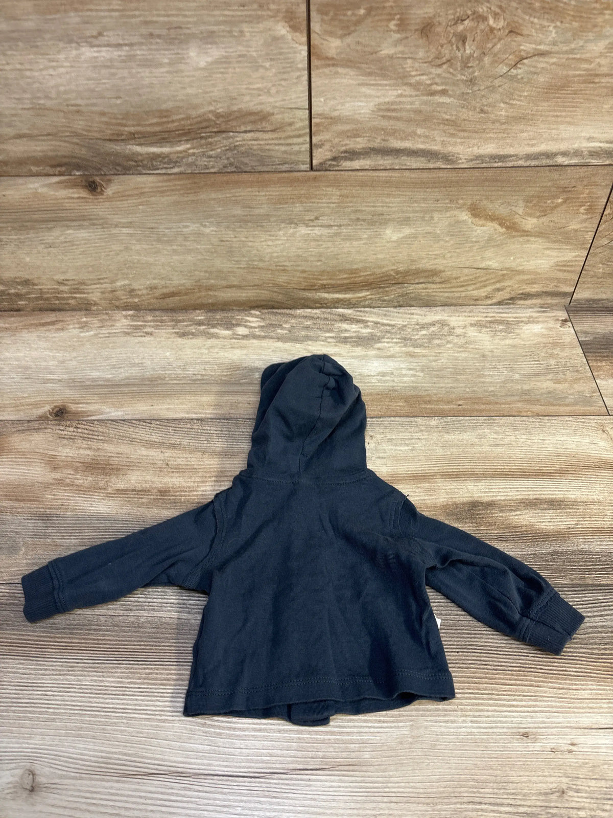 Back view of Carter’s newborn hooded button-front shirt showcasing hood and ribbed cuffs on wood background