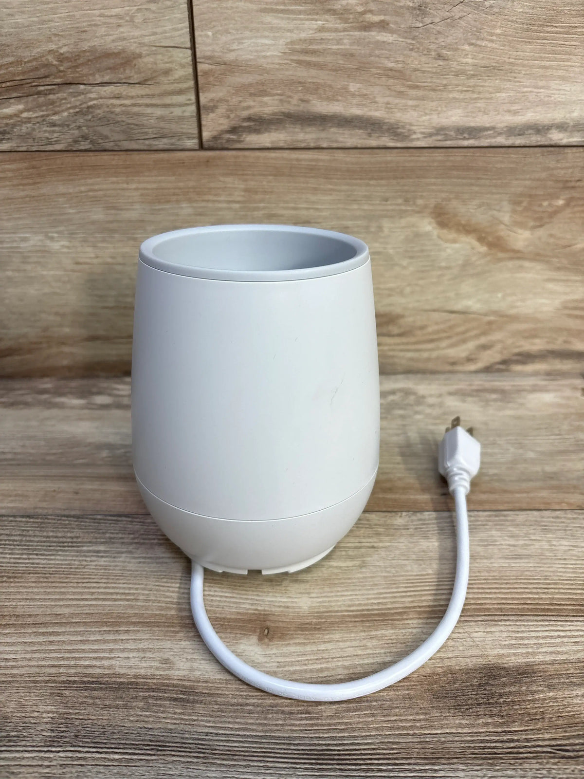 White Philips Avent Fast Baby Bottle Warmer with power cord on a wood surface