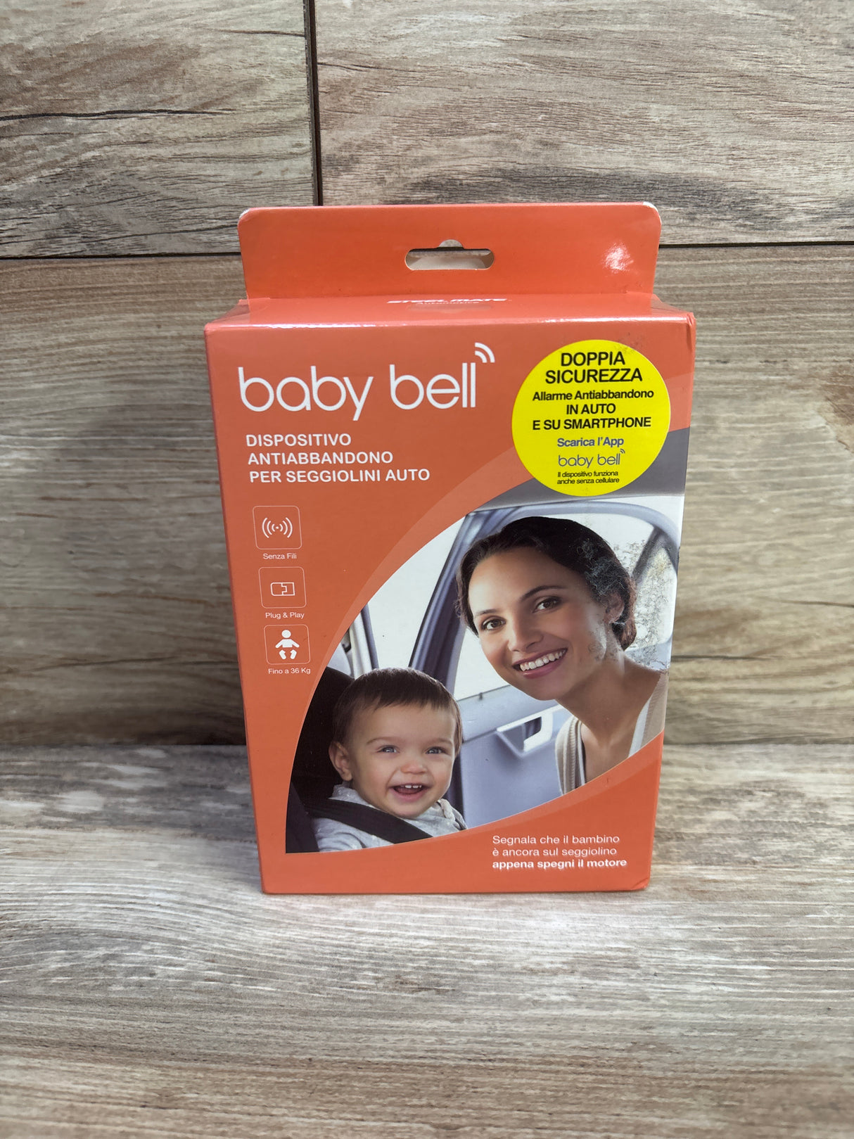 Front view of Baby Bell anti-abandonment device box with orange packaging and mother-and-baby photo on wooden background