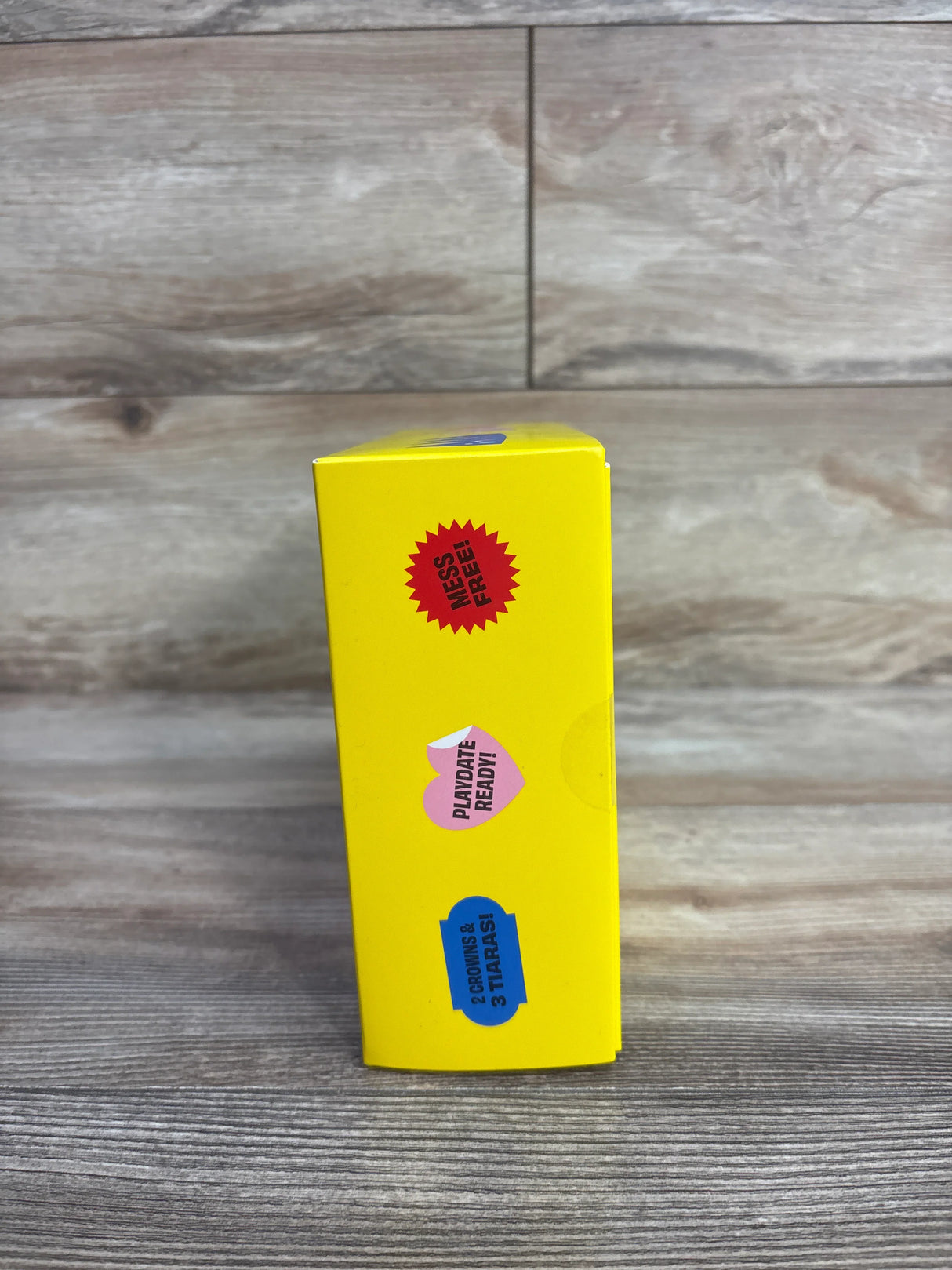Yellow product box with playful stickers and text on wood surface background