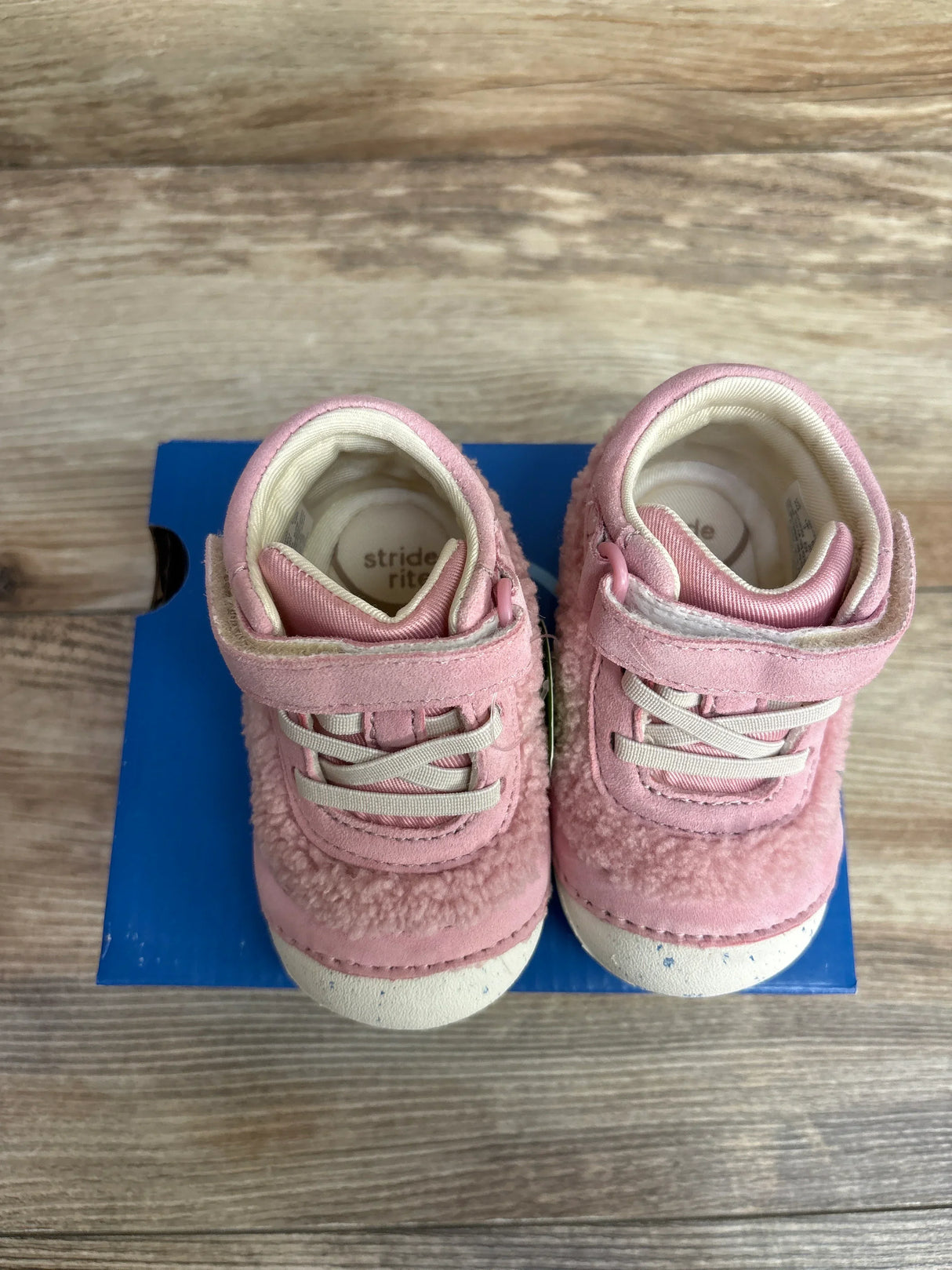 Top-down view of Stride Rite Sm Cedar toddler sneakers in pink showing sherpa upper and Velcro strap on blue shoebox