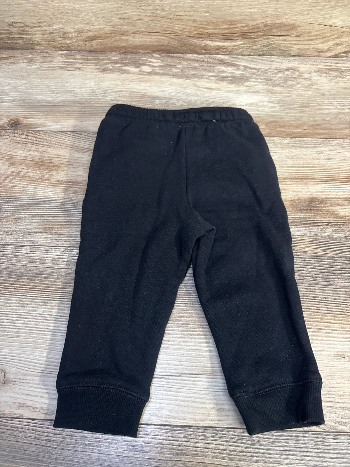 Front view of Cat & Jack drawstring joggers showcasing elastic waistband and ribbed cuffs on a wood background