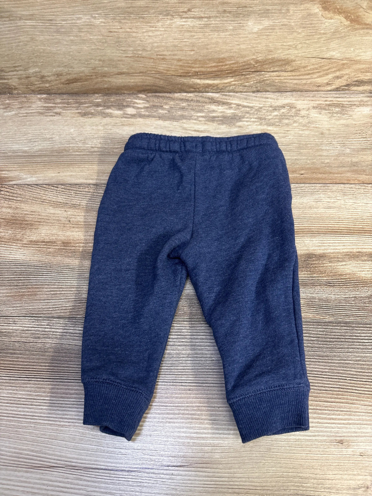 Front view of Cat & Jack drawstring joggers in size 12 months, showcasing an elastic waistband and ribbed cuffs on woodgrain