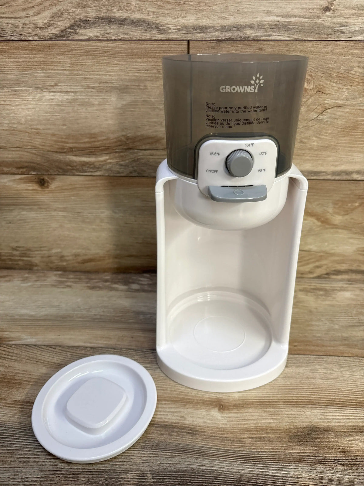 Front view of GROWNSY baby bottle warmer with tinted water tank, temperature dial, and removable lid on wood background