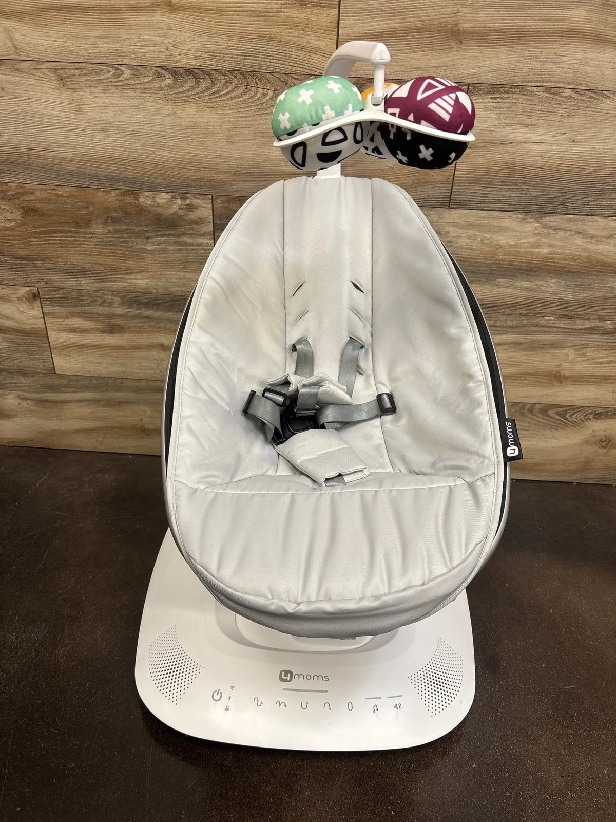 Front view of 4moms mamaRoo baby swing in grey showcasing padded seat, harness, control base, and hanging toy mobile