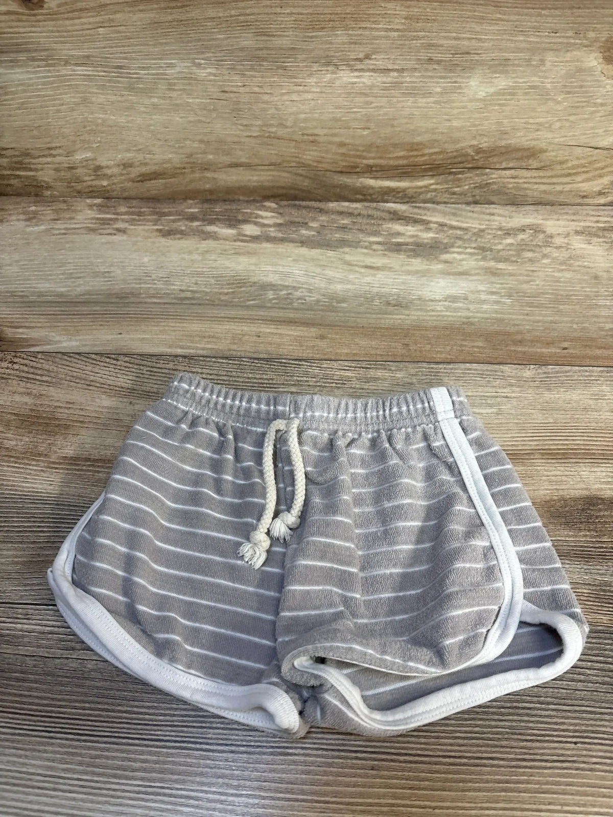 Gray and white striped toddler shorts with drawstring on wood background