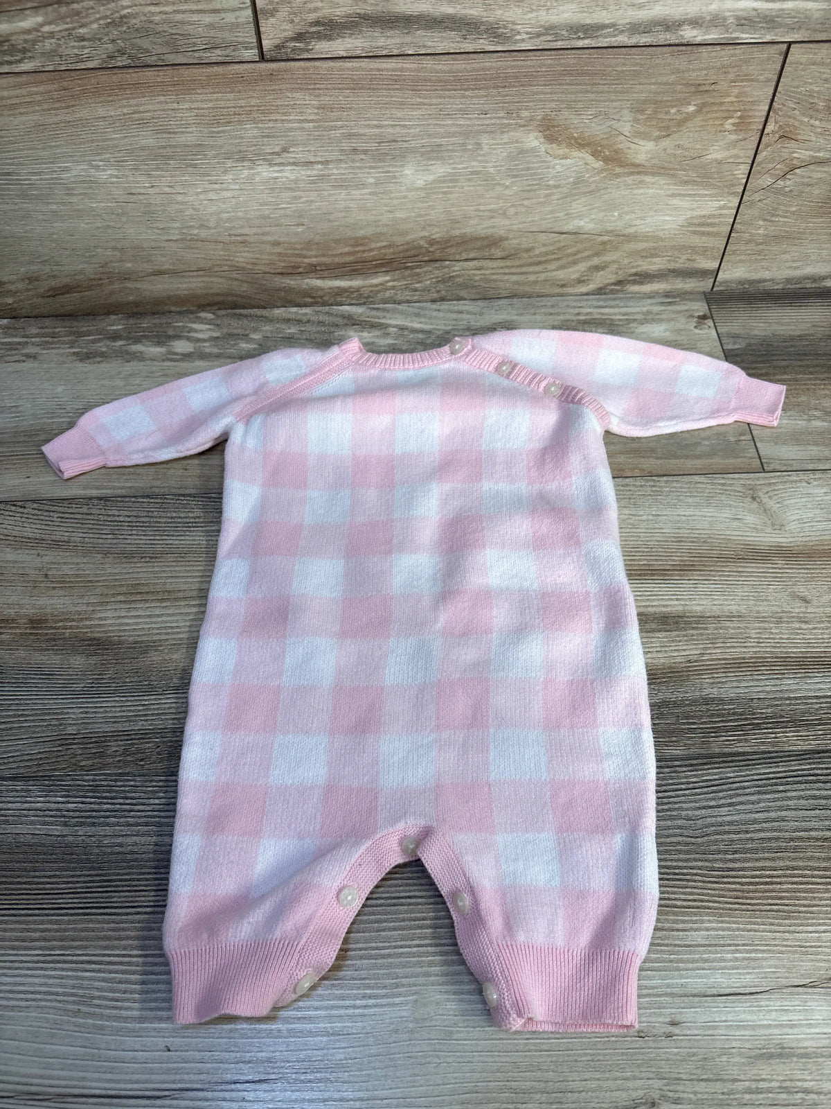 Front view of Ralph Lauren pink gingham cotton sweater coverall showcasing raglan sleeves and button closures on wood-grain background