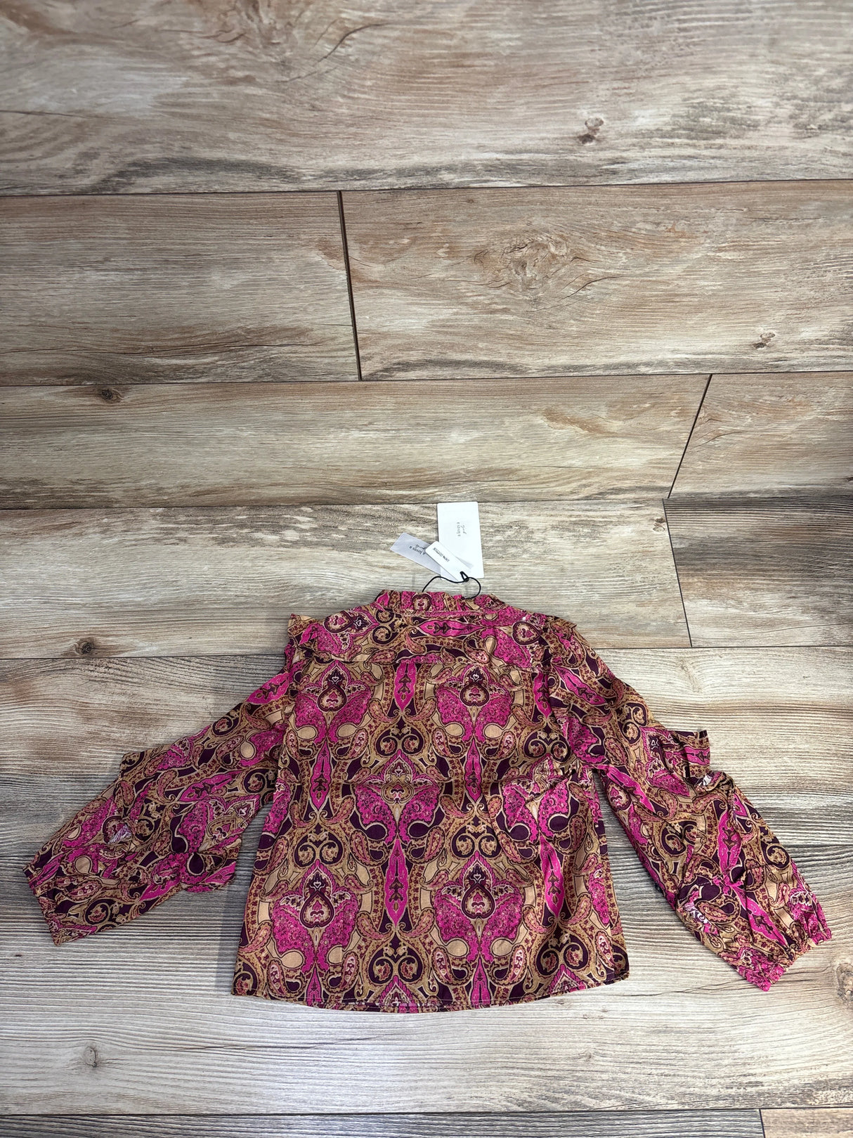 Pink and brown paisley long sleeve blouse with tags on wooden floor background