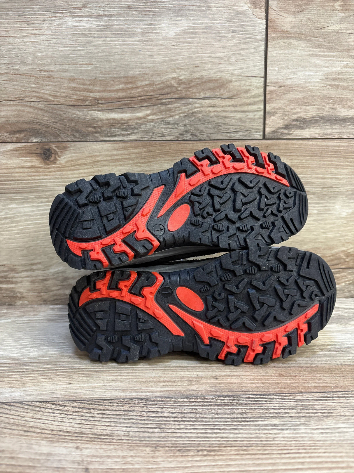 Sole view of NEW Cat and Jack Patsy Hiking Boots in black size 1Y showcasing red and black rugged lug tread pattern on wood plank floor