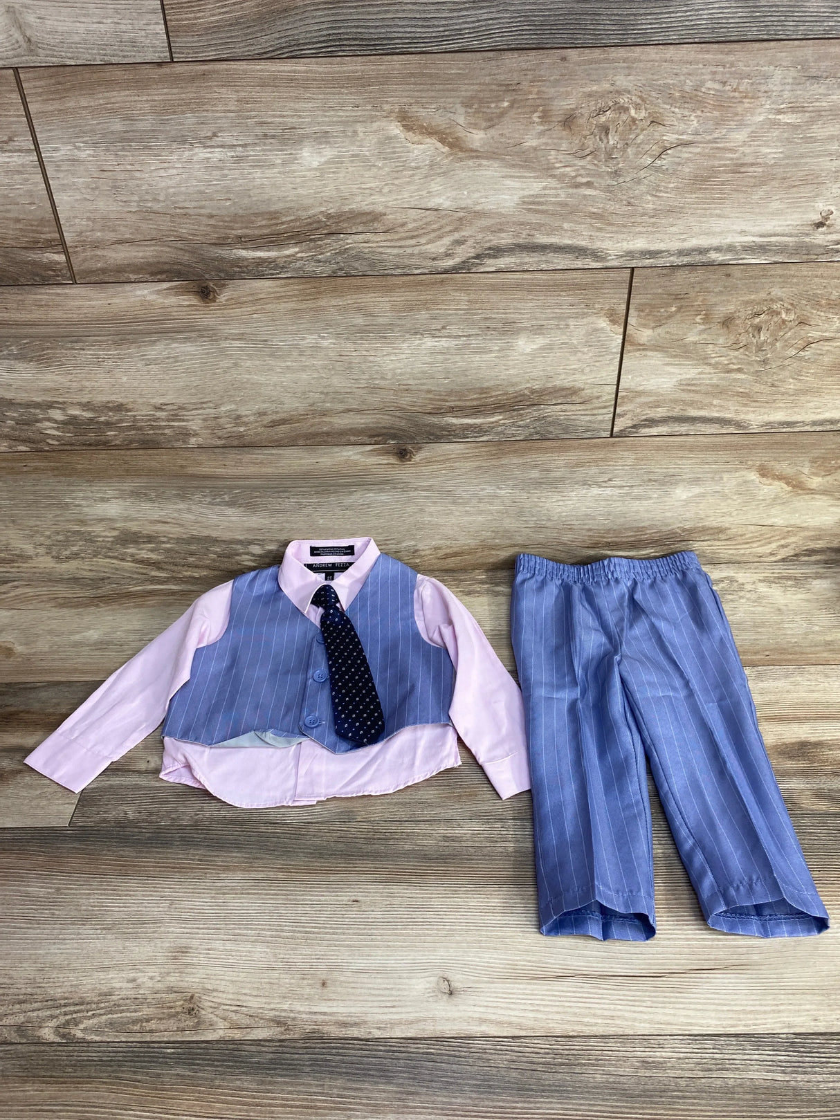 Flat lay of Andrew Fezza 4pc vest set: pink shirt, blue pinstripe vest and pants, navy polka dot tie on wood floor