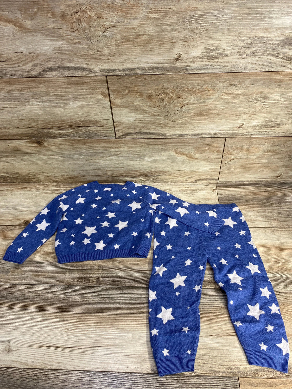 Blue kids sweater and pants set with white star pattern on wood background