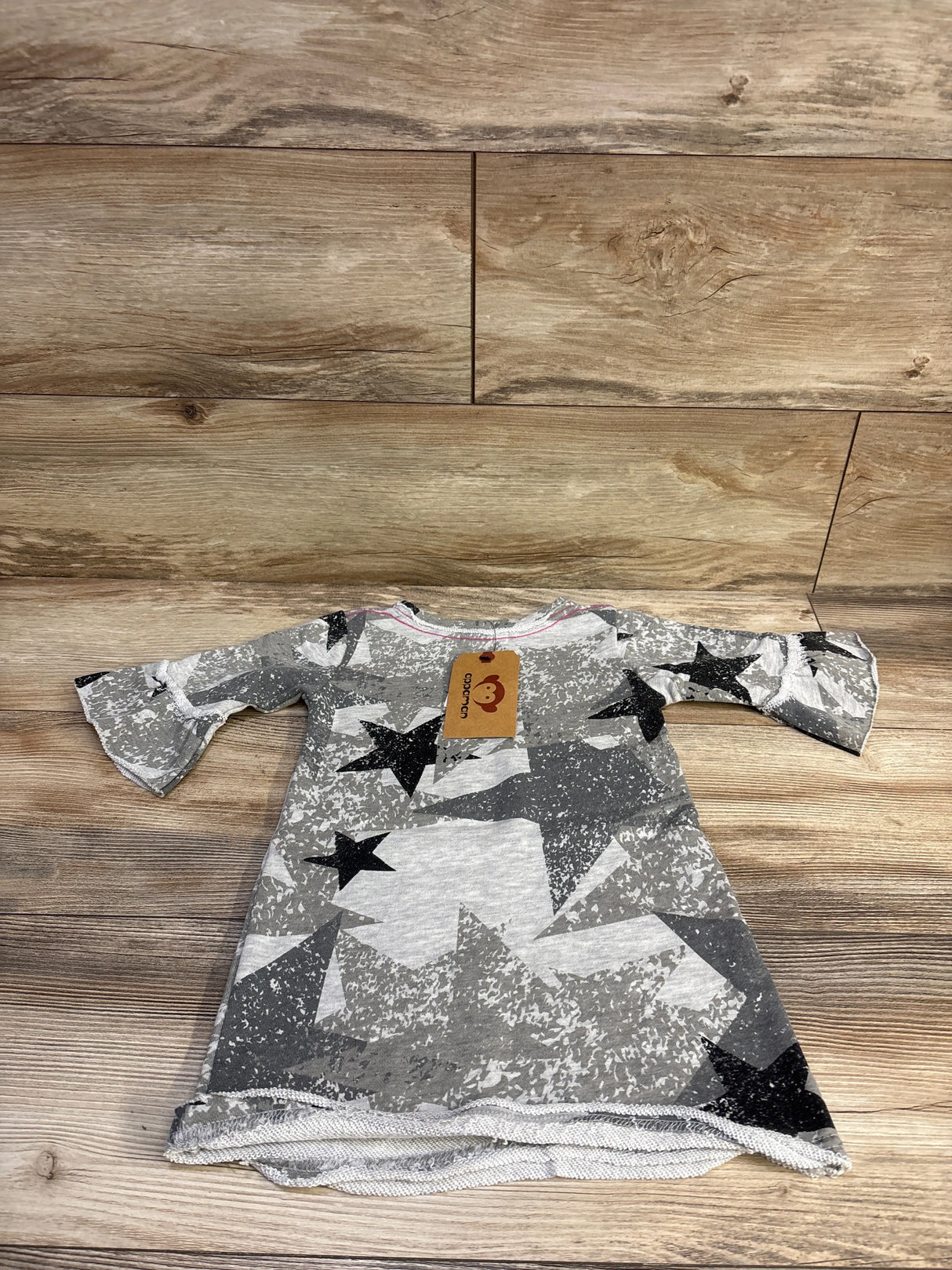 Flat lay of Appaman Kathleen toddler dress, size 4T, showing grey camo with black stars and bell sleeves on wood background