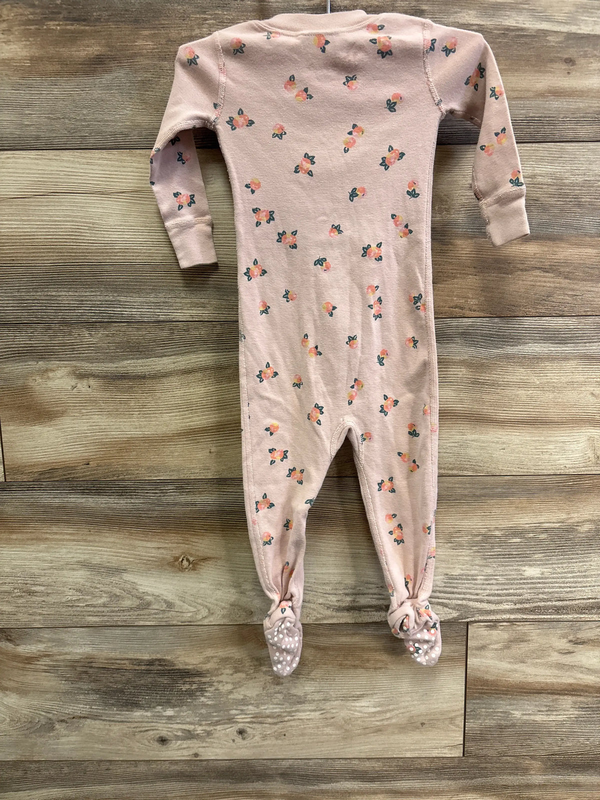 Front view of Hanna Andersson pink floral sleeper showcasing long sleeves, footed legs, and flatlock seams on a wood floor