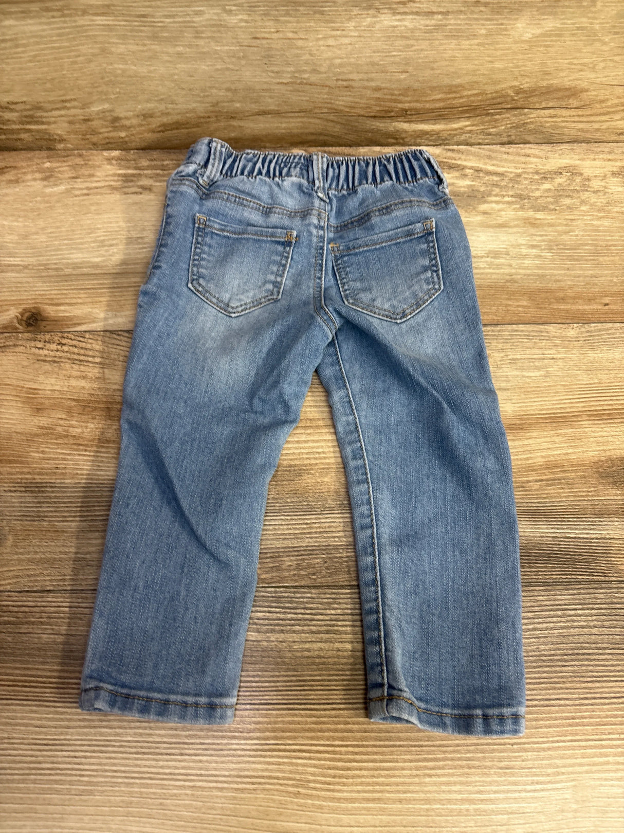 Back view of light blue toddler jeans with elastic waistband on wooden floor