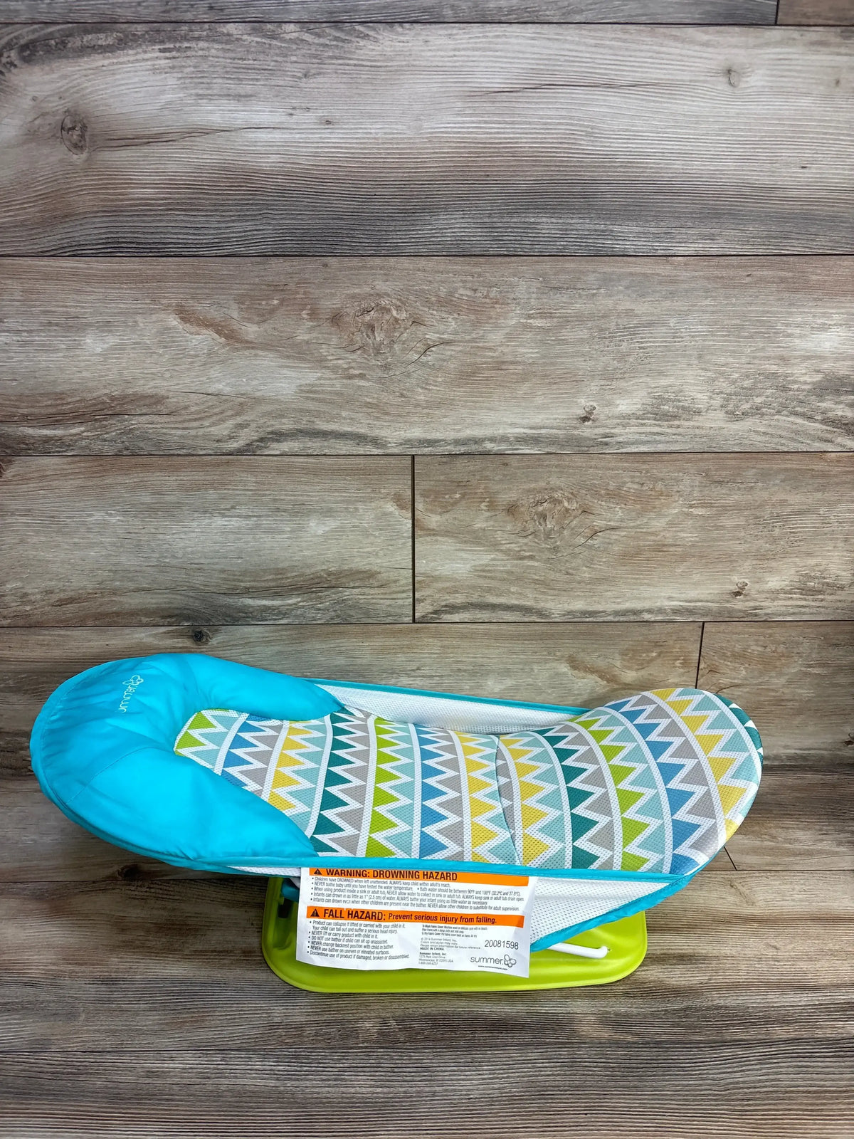 Side view of Summer Deluxe Baby Bather Green showcasing triangle print mesh seat with teal pillow on green frame on wood plank floor