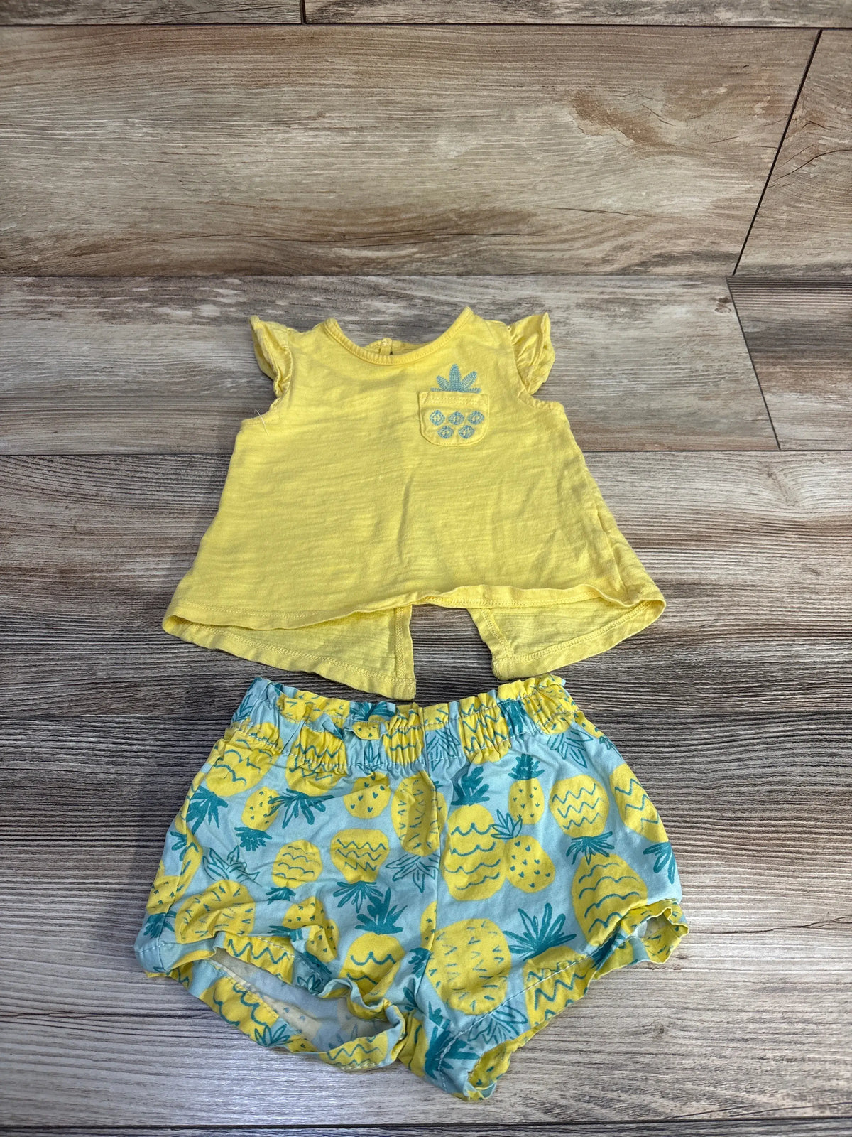 Flat lay of Just One You 2-piece pineapple tank top and shorts set showing yellow top and pineapple-print shorts
