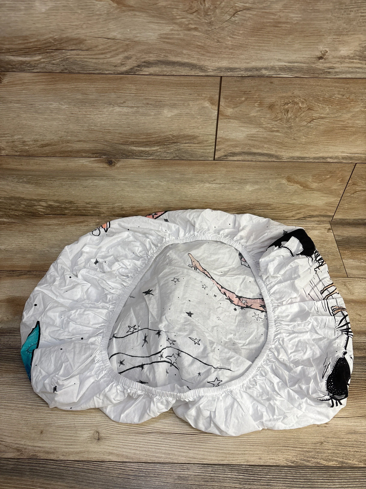 White fitted crib sheet with star and animal print on wood floor