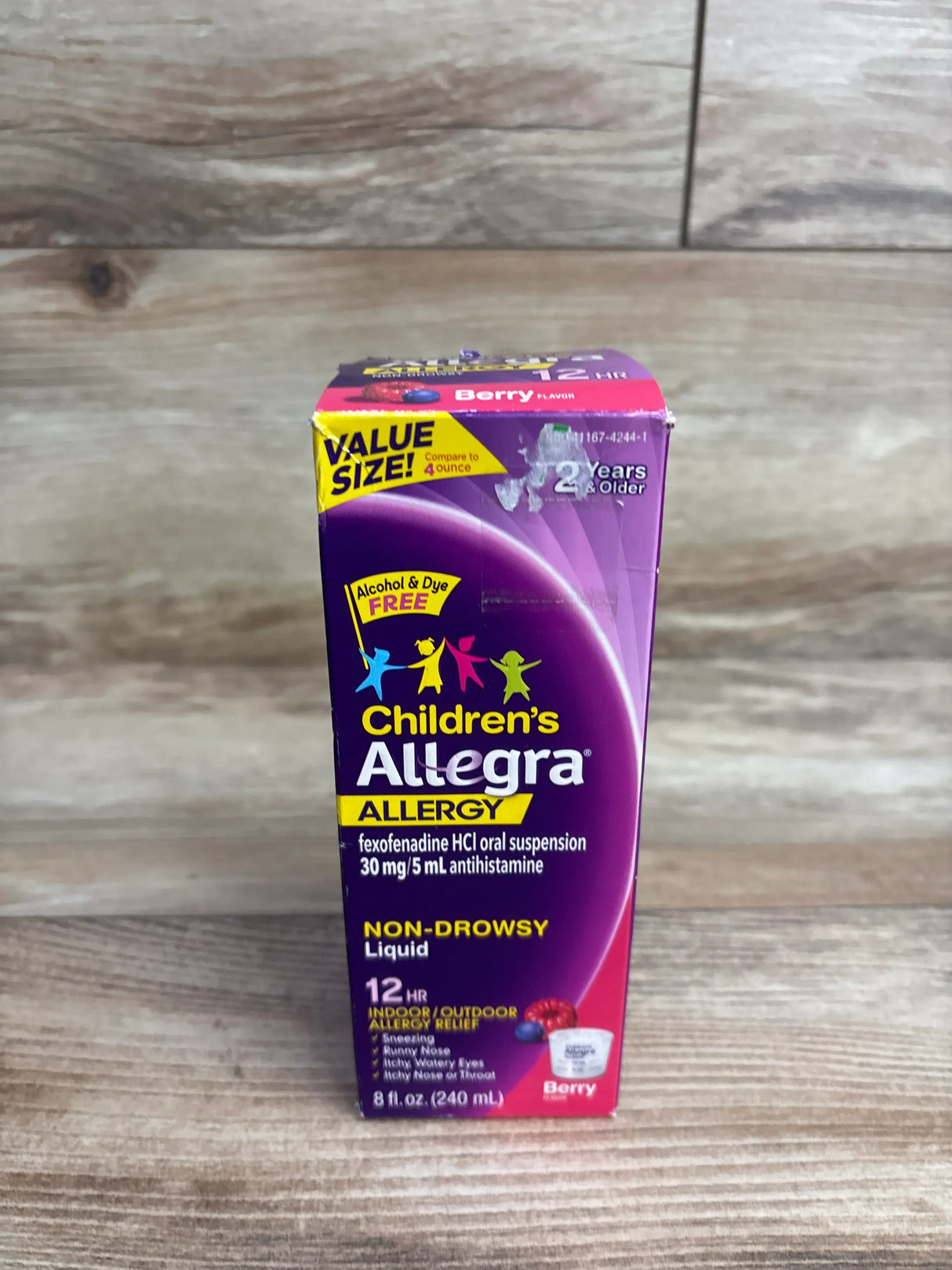 Front of Childrens Allegra 12-hour allergy liquid box showing Non-drowsy, 8 fl oz (240 mL), berry flavor on wood background