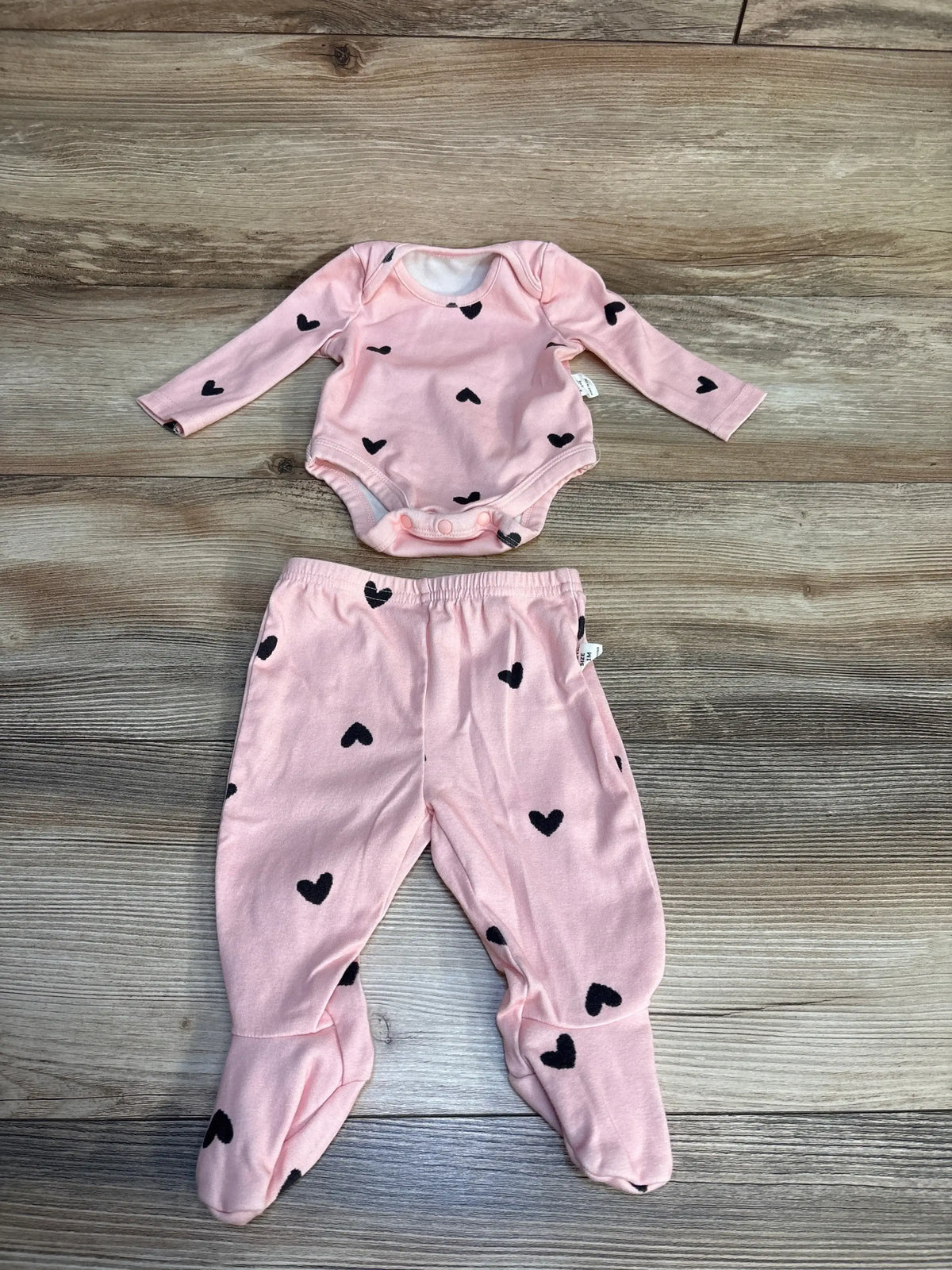 Pink baby outfit with black heart print, includes long sleeve bodysuit and footed pants