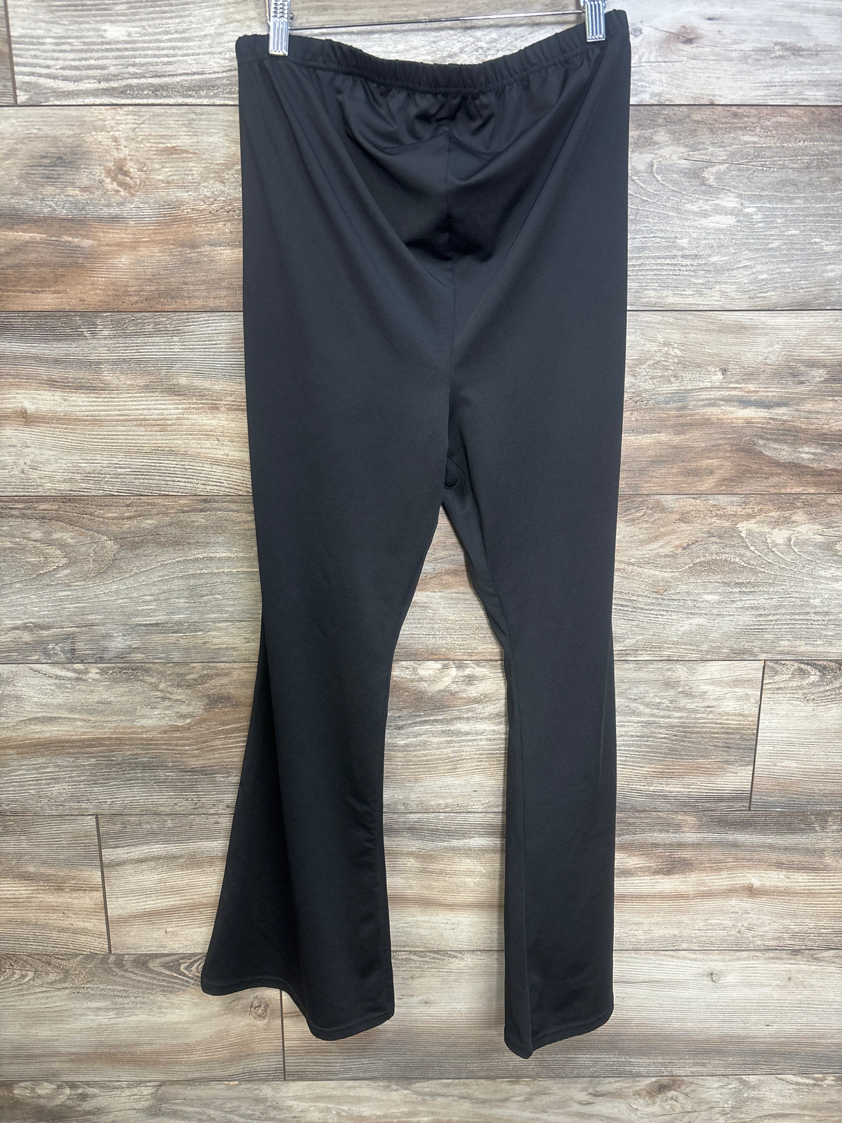 Front view of black maternity over belly yoga pants in XL showcasing the waistband and tapered legs on a wood look floor