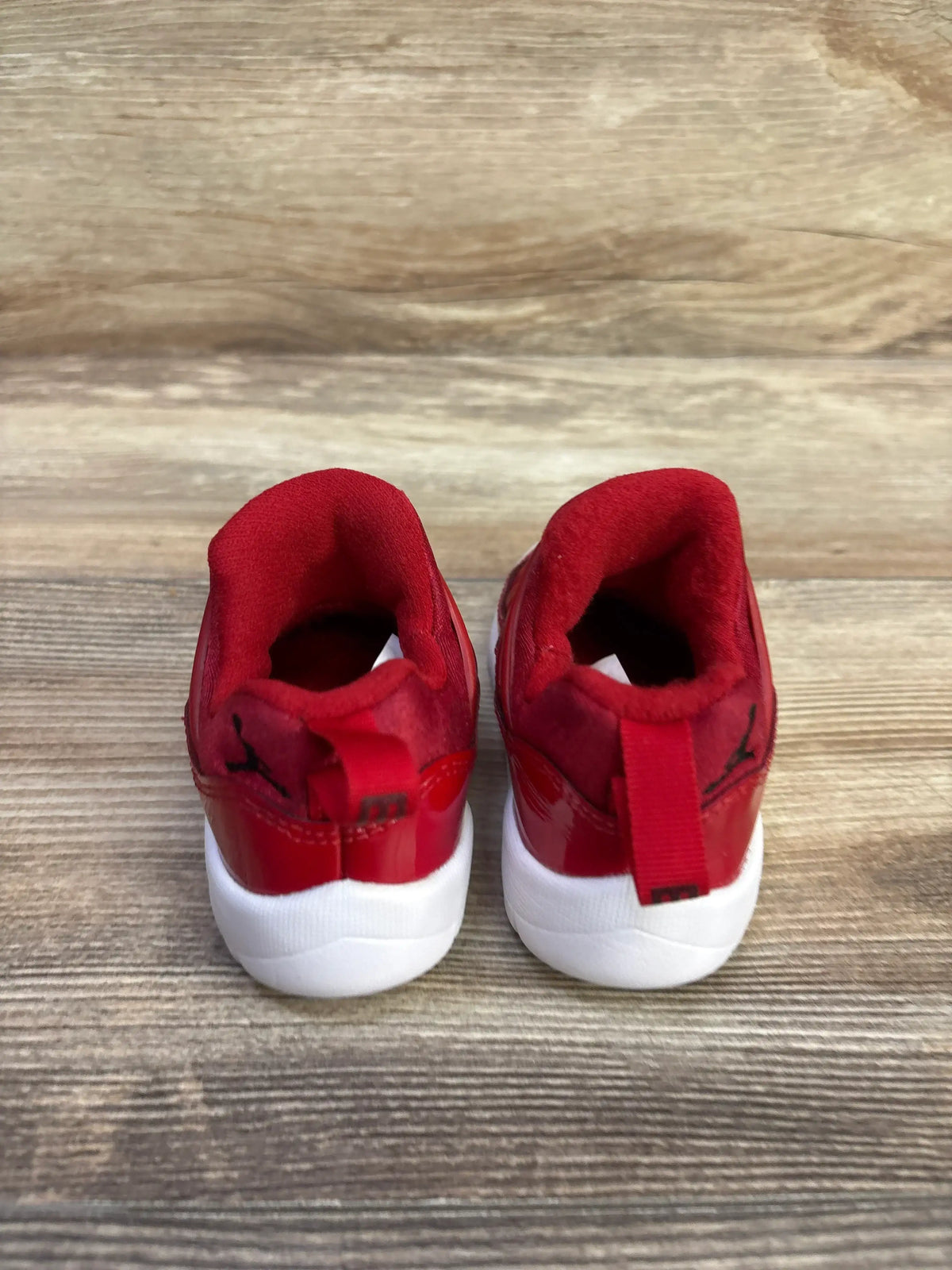 Rear view of Air Jordan 11 Retro Little Flex TD Gym Red sneakers with red uppers, white soles, and heel pull tabs
