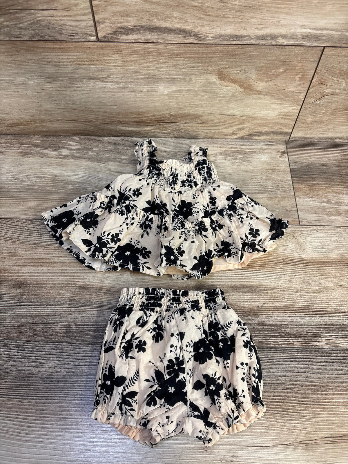 Overhead view of Haute Hippie cream Swiss dot top and shorts set with floral print and smocked bodice on wood floor