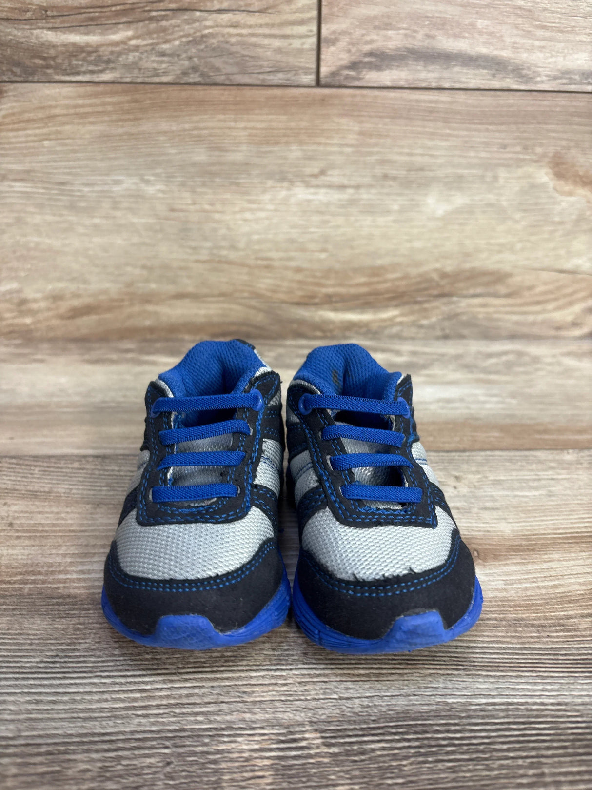 Blue and gray toddler sneakers with black trim on wood floor