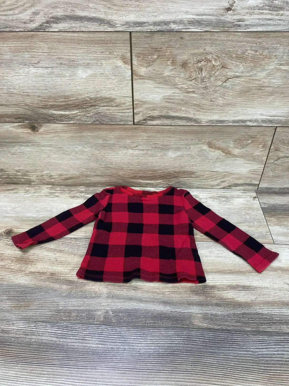 Flat lay of Old Navy toddler red and black buffalo check thermal shirt showing waffle knit and crew neck on wood background
