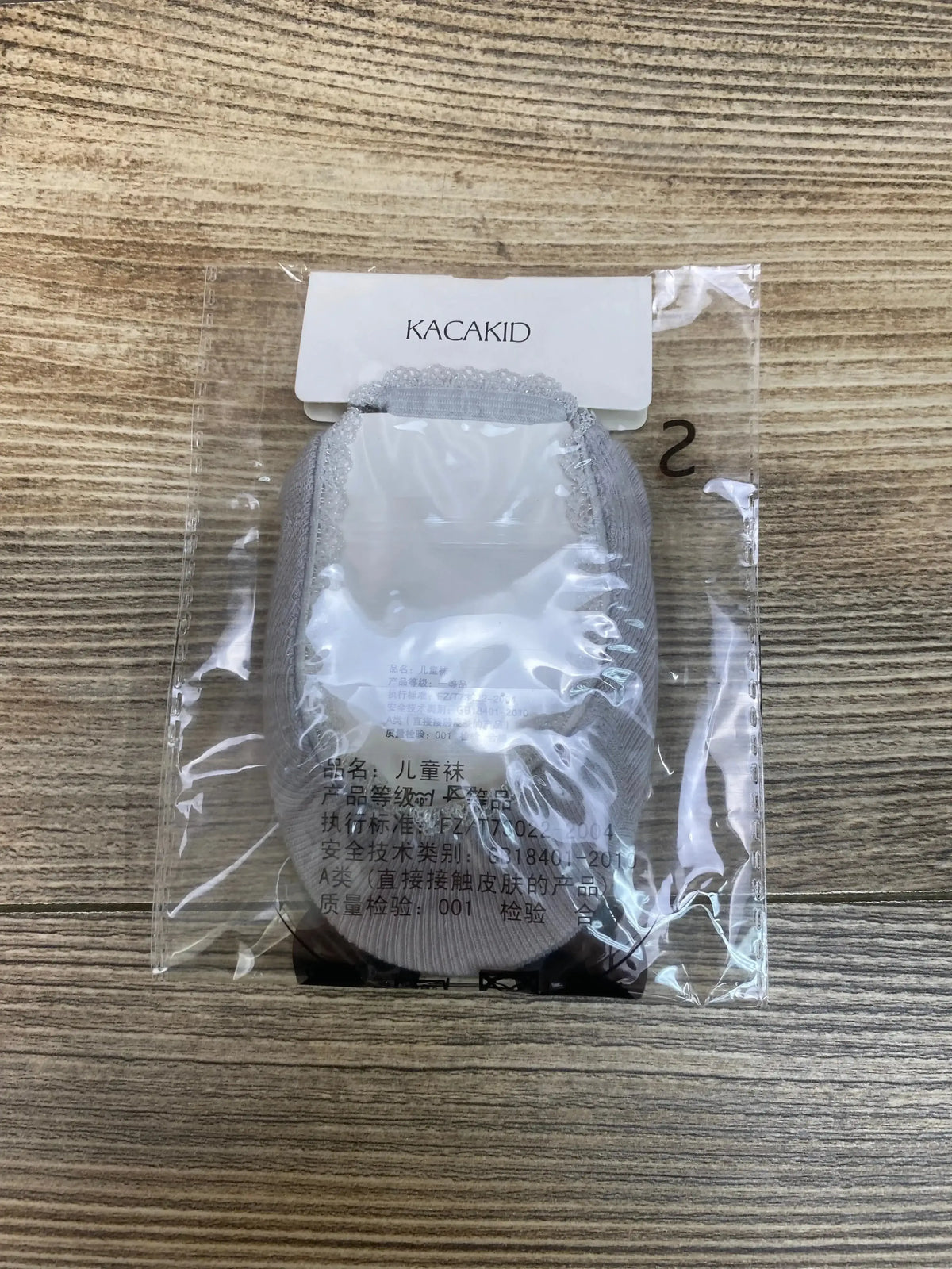 Top view of NEW Kacakid Princess Mary Jane Dress Socks Grey Sz 3-12m showcasing grey knit socks in sealed original packaging on wood plank floor