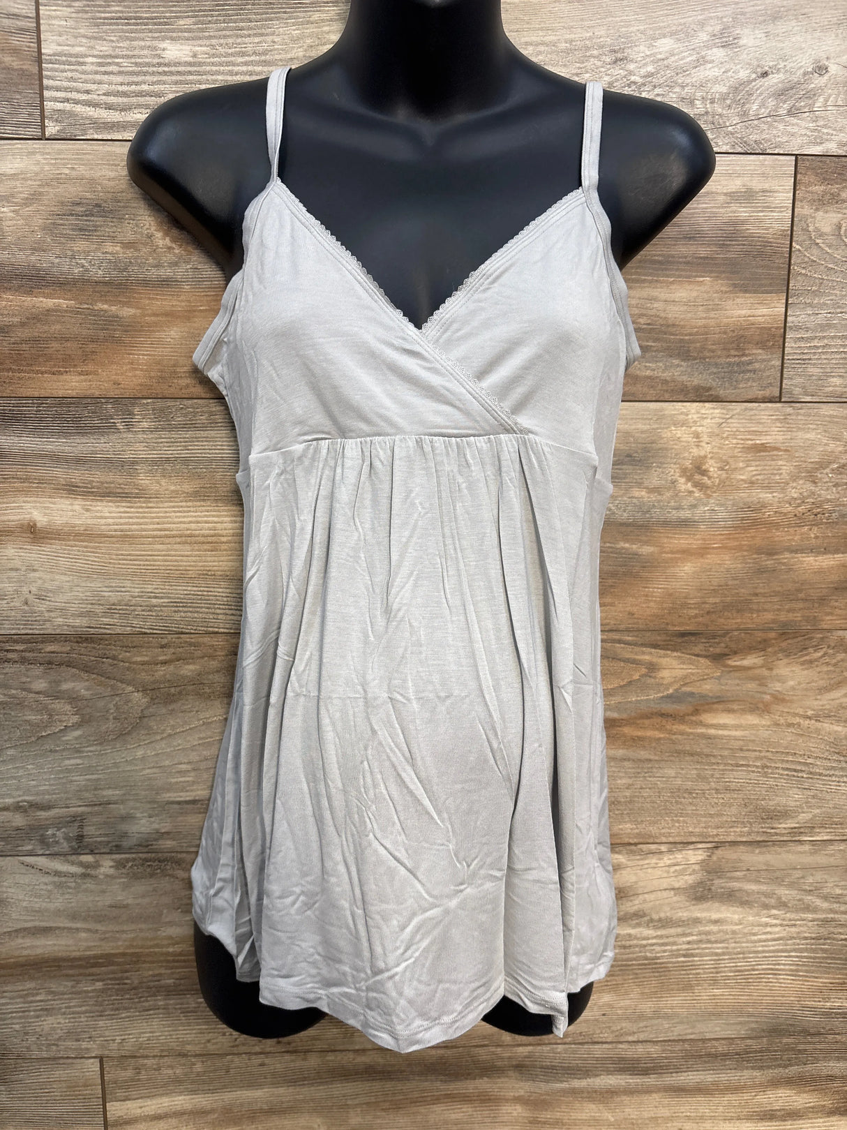 Light gray sleeveless camisole top with spaghetti straps on a mannequin, wood background