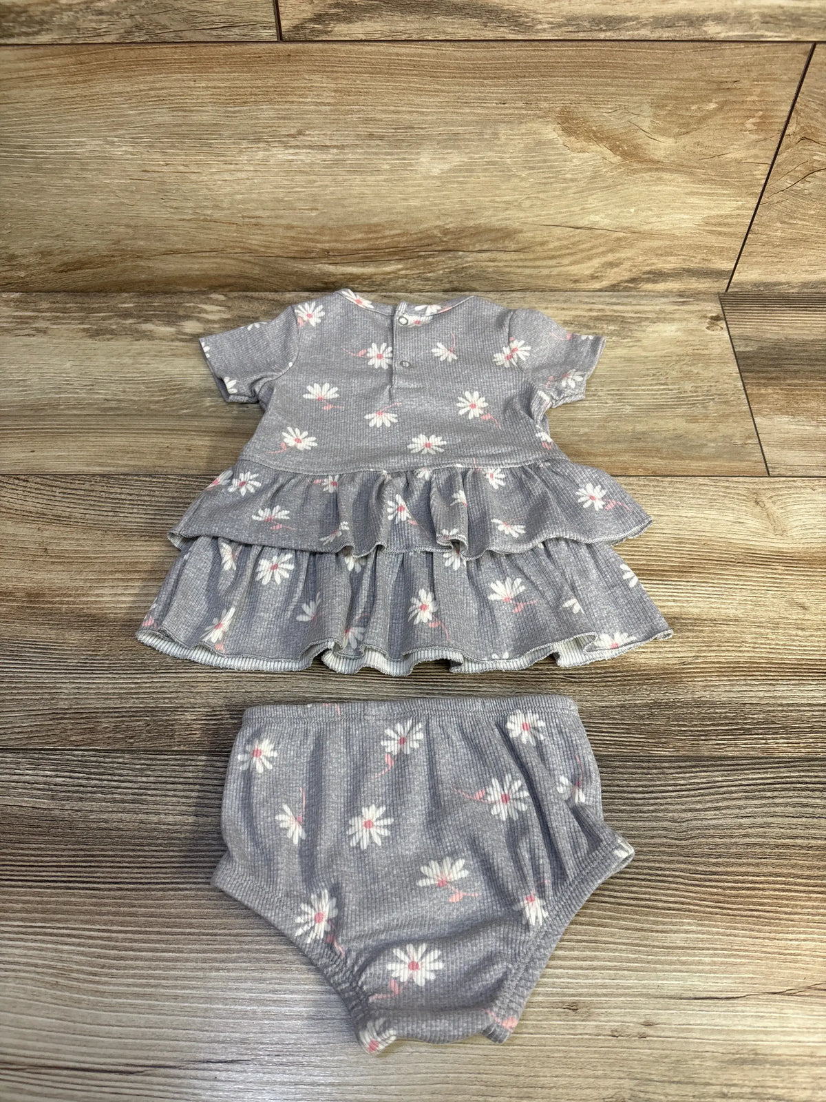 Front view of Modern Moments floral dress and bloomers set showing ribbed grey fabric and ruffles on a wood floor